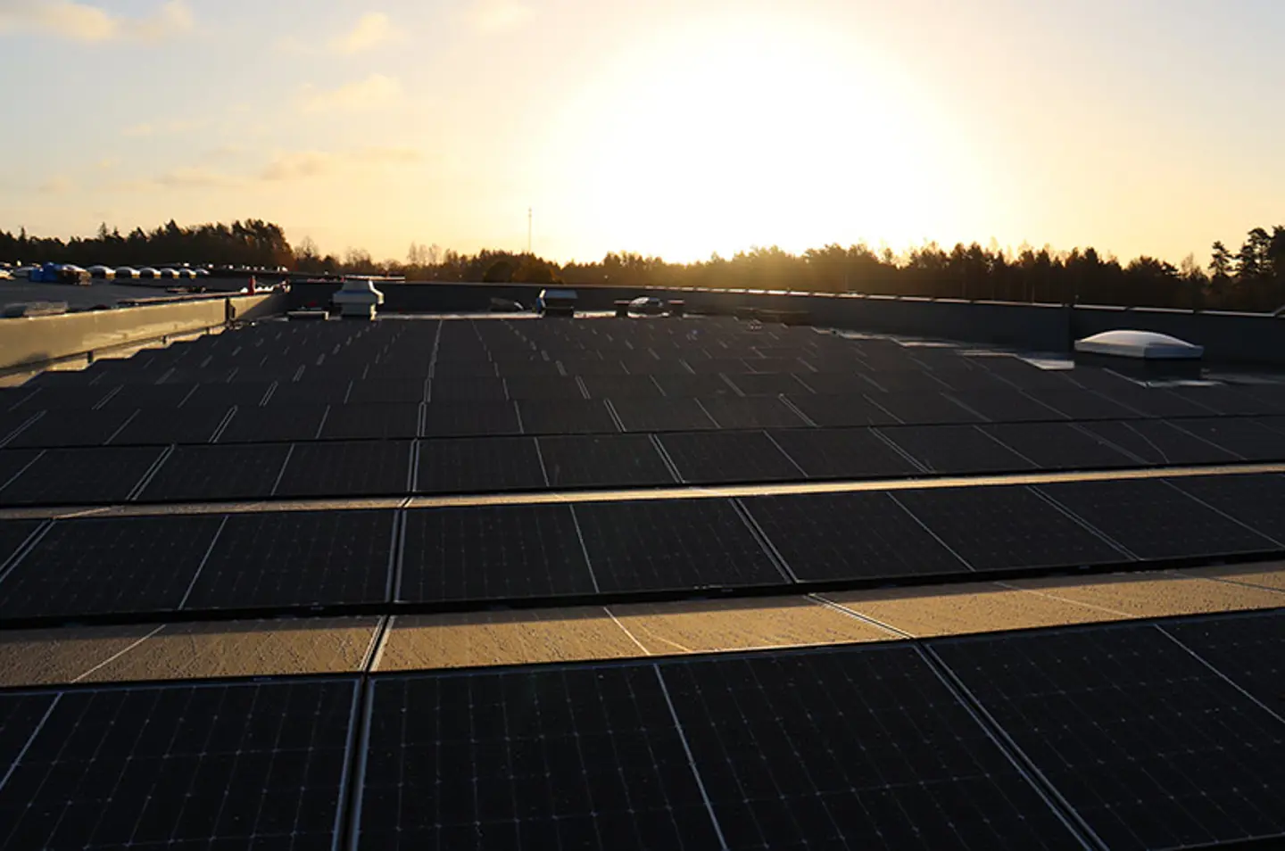 Solar panels shown mounted to the top of Axelent's building. The sun is setting in the background.